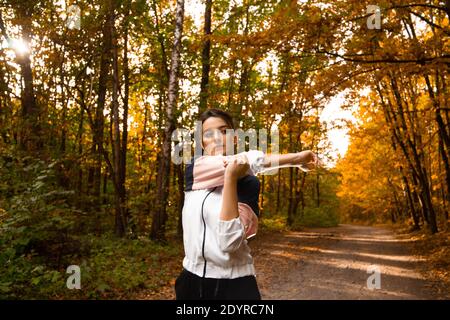 Une athlète féminine s'échauffe avant un entraînement intensif. Un mode de vie sain. Fitness femme sportive s'étirant avant de courir tôt le matin dans la forêt Banque D'Images