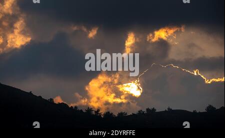 Coucher de soleil avec ciel nuageux et soleil caché derrière le nuages Banque D'Images