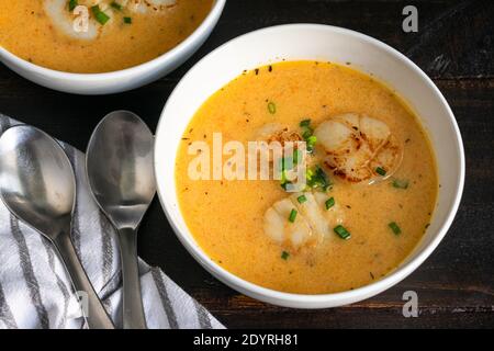 Bols de bisque irlandais de noix de Saint-Jacques : deux bols de bisque de fruits de mer recouverts de ciboulette et trois coquilles Saint-Jacques Banque D'Images