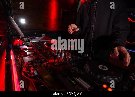 Le DJ se donne sur la terrasse de l'équipement et sur le mixeur lors de la fête. Coupe de disque jockey en noir hoody mélangeant de la musique en boîte de nuit. Concept de vie nocturne. Avec Banque D'Images