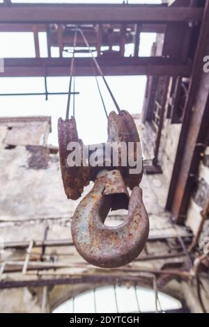 détail d'une ancienne grue industrielle avec crochet dans un salle industrielle abandonnée détruite Banque D'Images