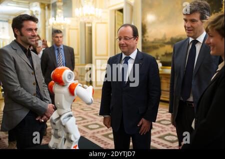 Le président français François Hollande est détenteur d'un robot humanoïde Nao de la société Aldebaran Robotics lorsqu'il visite une exposition sur le design et la technologie industriels français à l'Elysée Palace de Paris, France, le 12 septembre 2013. Chez R, ministre français de la reprise industrielle Arnaud Montebourg. Photo de Thierry Orban/ABACAPRESS.COM Banque D'Images