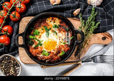 Petit déjeuner avec œufs et tomates. Shakshuka dans un récipient. Plats traditionnels turcs. Arrière-plan gris. Vue de dessus Banque D'Images