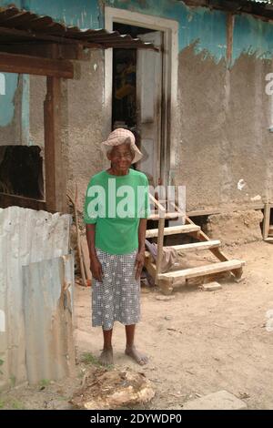 Ocho Rios, Jamaïque. femme de 81 ans debout devant sa maison sans chaussures. Banque D'Images
