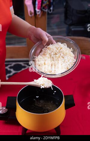 Préparation du fromage suisse versé dans l'huile pour la fondue pour le trempage du pain Banque D'Images