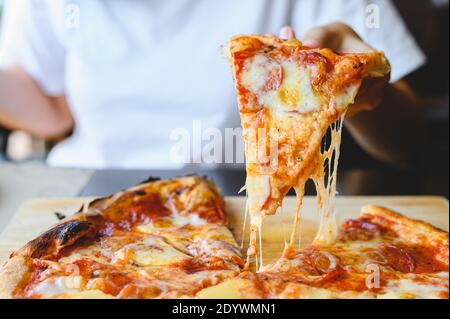 Pizza au feu de bois à la main. Pizza hawaïenne traditionnelle et salami savoureux plat saveur d'origine restaurant italien. Four à bois Pizza wi Banque D'Images