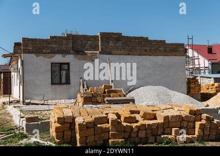 Une pile de briques se trouve devant la maison en cours de construction. Banque D'Images