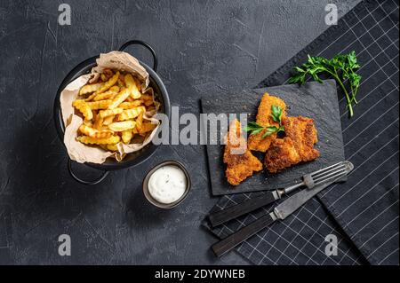 Faire frire le filet de morue et les frites. Arrière-plan noir. Vue de dessus Banque D'Images