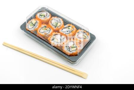 Nourriture japonaise facile, petits pains à sushi prêts à manger dans un contenant en plastique avec baguettes, image sur fond blanc. Banque D'Images