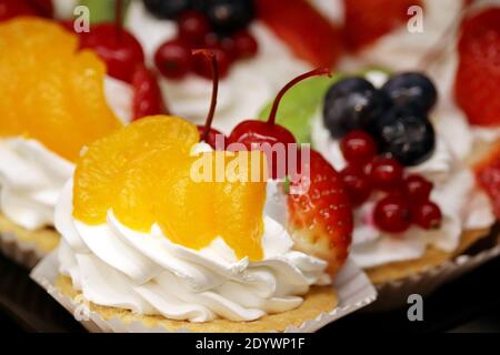 Gâteau crémeux aux fruits frais et aux baies. Dessert sucré avec mandarines, fraises, cerises et bleuets Banque D'Images