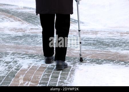 Homme âgé avec canne à pied dans une rue d'hiver. Concept de chaulage, de vieillesse, de neige Banque D'Images