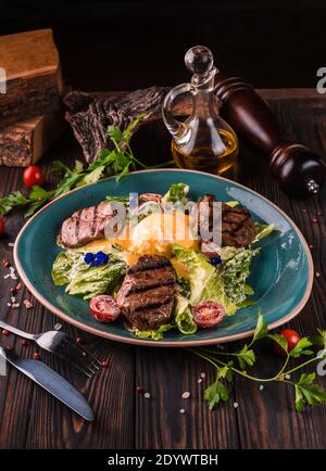 Œufs benedict avec viande de boeuf sur une grande assiette blanche. Petit-déjeuner anglais traditionnel avec œufs Benedict, tomates cerises et laitue. Œuf Benedict servi Banque D'Images