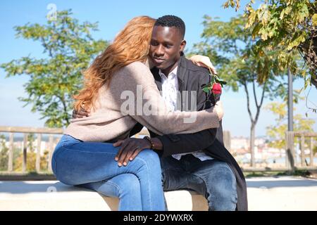 Homme noir africain et femme caucasienne à tête rouge embrassant avec une rose. Jeune couple multiracial célébrant la Saint Valentin. Banque D'Images