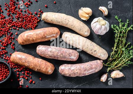 Assortiment de saucisses fraîches crues aux épices. Arrière-plan noir. Vue de dessus Banque D'Images