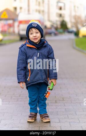 POZNAN, POLOGNE - 25 décembre 2020 : jeune garçon tenant un train de jouets debout sur un trottoir dans la ville Banque D'Images