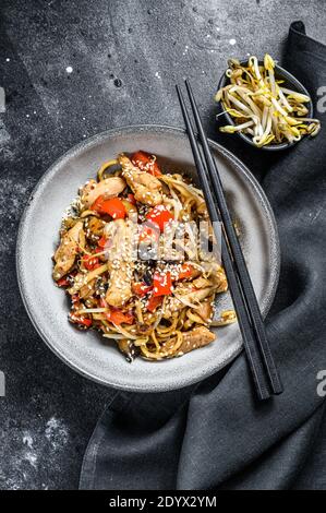 Poulet sauté. Wok nouilles udon. Cuisine asiatique traditionnelle. Arrière-plan noir. Vue de dessus Banque D'Images