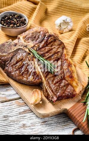 Steak de Porterhouse grillé sur une planche à découper. Viande de bœuf cuite. Fond en bois blanc. Vue de dessus Banque D'Images