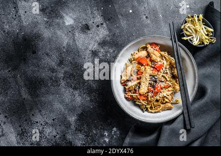 Nouilles sautées Udon avec viande de poulet et sésame. Arrière-plan noir. Vue de dessus. Copier l'espace Banque D'Images