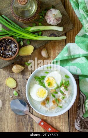 Soupe chaude de poulet avec du riz au gingembre et de l'ail dans un bol sur une table rustique. Plan d'étapage avec vue de dessus. Banque D'Images