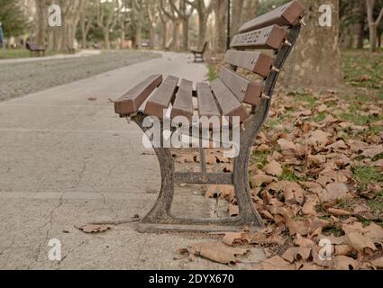 Chaise de rue de style ancien et rétro en bois avec feuilles séchées au sol et thème de l'automne. Banque D'Images