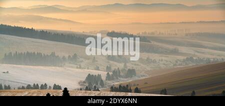 Magnifique paysage de Slovaquie - champs ondulés, montagnes, soufflées de neige, enveloppées de brume matinale Banque D'Images