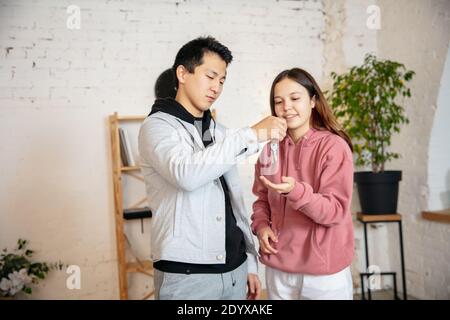 Obtention des clés. Nouveaux propriétaires, jeune couple déménagement à la nouvelle maison, appartement, look heureux. Rêve, amour, relation, immobilier et concept intérieur. Nouvelle vie ensemble. Femme caucasienne et homme asiatique. Banque D'Images