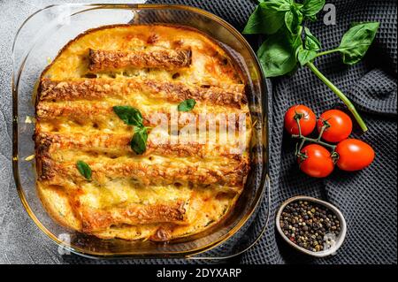 Cannelloni à la viande avec sauce tomate et fromage. Cuisine italienne. Arrière-plan gris. Vue du dessus Banque D'Images