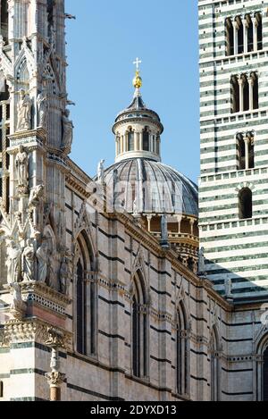 Façade magnifiquement décorée de la cathédrale de Sienne à la lumière du soleil contre le ciel bleu, Toscane, Italie Banque D'Images