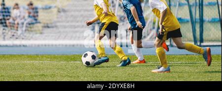 Jeu de football Kicking pour Garçon sur le terrain de l'école. Jeunes joueurs de sport anonymes jouant au football lors d'une journée d'été Banque D'Images