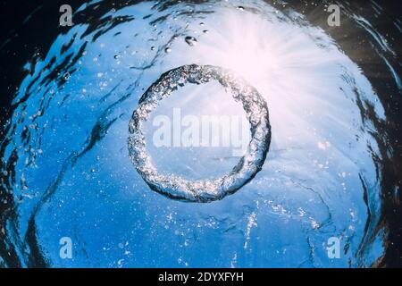 Bulle d'anneau sous l'eau et le soleil dans l'océan bleu. Texture de l'eau. Banque D'Images