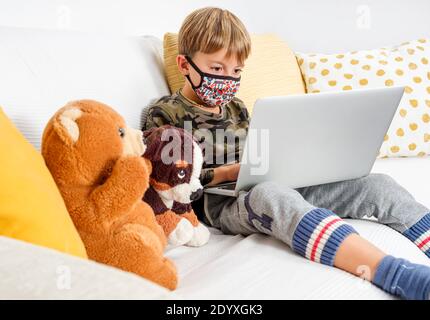 Enfant étudiant à la maison, porter un masque de protection et faire des devoirs à l'école Banque D'Images