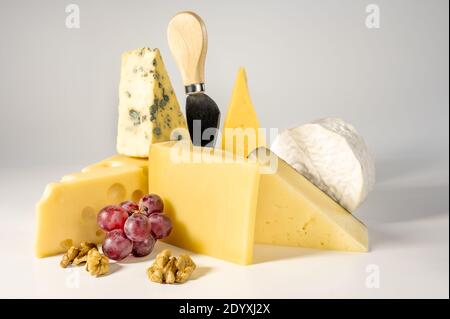 Composition de différents types de fromages avec noix et raisins sur fond blanc. Fromage bleu Dorblu, Suluguni fumé, brie, Maasdam, cheddar, par Banque D'Images