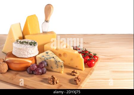 Assortiment de différents types de fromages avec noix, tomate et raisins isolés sur fond blanc. Fromage bleu Dorblu, Suluguni fumé, brie, Maasd Banque D'Images