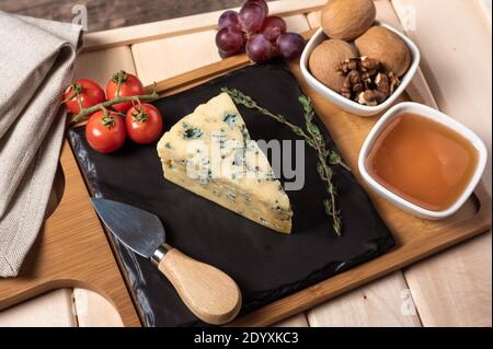 plateau en bois pour le petit déjeuner avec fromage bleu, miel, noix, tomate. plateau en bois avec assiette noire Banque D'Images