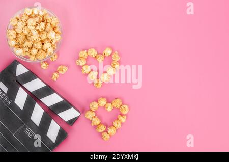 Concept de film de la Saint-Valentin. Papperboard de cinéma avec coeurs de pop-corn caramel avec espace pour les copies sur fond rose. Banque D'Images