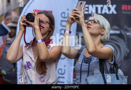 18 août 2018. Moscou, Russie. Deux filles dans une rue très fréquentée prennent des photos avec leur téléphone et leurs appareils photo de quelque chose d'intéressant ci-dessus. Banque D'Images