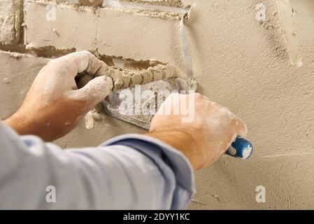 Professional Builder moulage de carreaux décoratifs sur le mur de plâtre gips . travailleur enlever le ruban sous le plâtre pour imiter la brique décorative sur le mur Banque D'Images