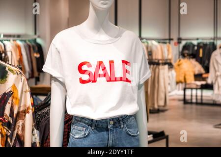 Mannequin d'une femme dans une chemise blanche et jeans avec inscription rouge dans un magasin de vêtements. Promotion, publicité, shopping et vendredi noir con Banque D'Images