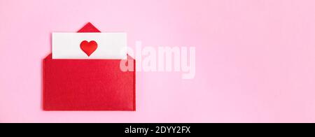 Bannière rouge enveloppe ouverte avec une feuille de papier avec un coeur sur un fond rose avec un espace de copie. Concept de Saint-Valentin et notes d'amour, chri Banque D'Images