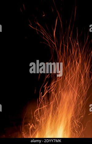 Étincelles provenant d'un incendie sur fond de nuit sombre. Feu de joie. Photo verticale Banque D'Images