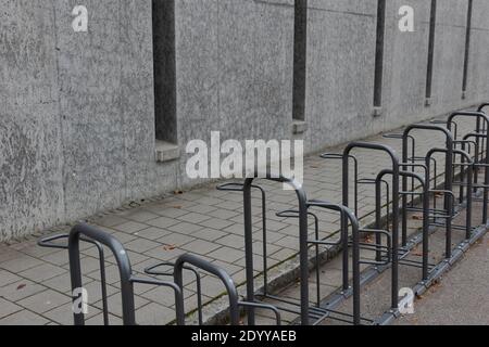 Longue rangée de porte-vélos vides près du trottoir école publique fermée avec mur de conrete gris sombre pendant l'hiver vacances scolaires de noël Banque D'Images