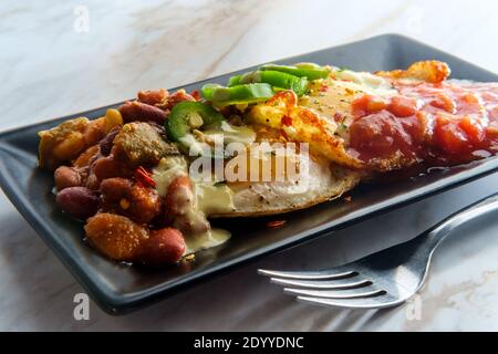 Deux œufs mexicains frits avec piment salsa et jalapeno en tranches servi huevos style rancheros Banque D'Images