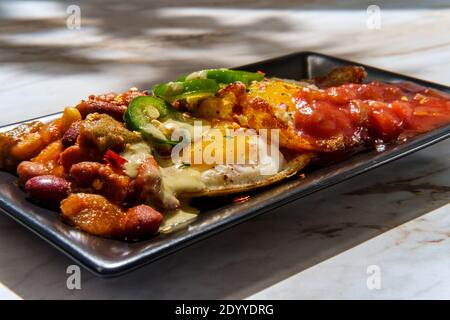 Deux œufs mexicains frits avec piment salsa et jalapeno en tranches servi huevos style rancheros Banque D'Images