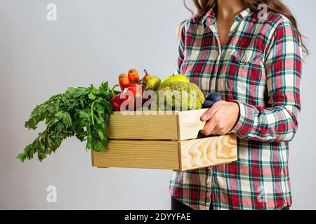 Femme tenant une boîte pleine de fruits et légumes sur blanc arrière-plan Banque D'Images