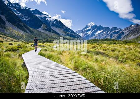 Les marcheurs marchent le long de la promenade de la piste de Hooker Valley dans le parc national de Mt Cook, en Nouvelle-Zélande, lors d'une journée d'été ensoleillée. Banque D'Images