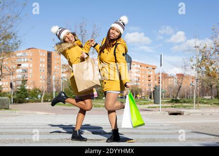 Deux jeunes femmes posant avec leurs sacs d'achats au milieu de la rue. Concept de style de vie. Banque D'Images