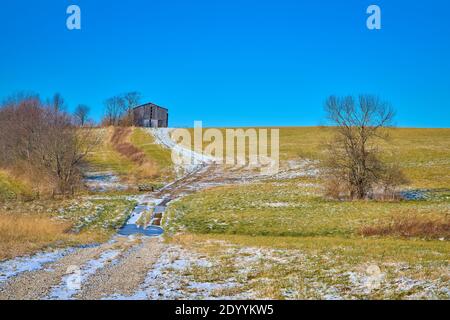 Grange de tabac assise sur une colline avec un sentier couvert de neige. Banque D'Images