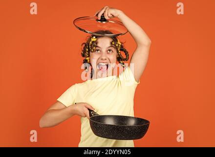 bonne enfance. gaie enfant avec des pillards. ménage de l'enfance. petite femme tient la poêle. cuisine dans la cuisine. concept de ménage. cuisine pour enfants à la maison. Banque D'Images