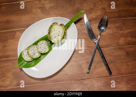 pitaya, fruit exotique mexicain vert et blanc, sur une assiette blanche avec fourche et couteau Banque D'Images