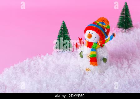 Bonhomme de neige et paysage hivernal minimal sur fond rose clair. Concept de vacances d'hiver. Banque D'Images